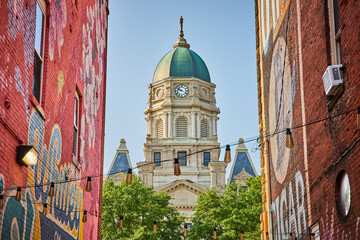 Columbia City courthouse framed by two buildings with wall murals in alleyway with lights © Nicholas J. Klein