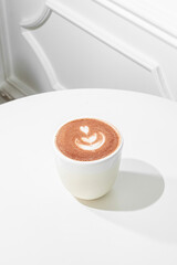 Cappuccino on a white table, sunny hard light.