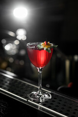 Club alcoholic cocktail in drinking glass decorated with flower isolated on dark background.
