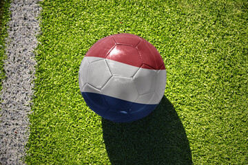 football ball with the flag of netherlands on the green field near the white line