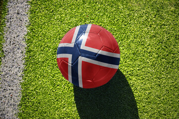 football ball with the flag of norway on the green field near the white line