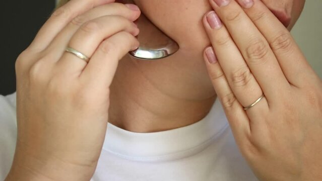 Close up of a caucasian woman using a metal gua she tool for lifting the face