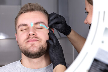 Depilation of the face with warm wax. A female eyebrow stylist applies melted wax to the eyebrows...