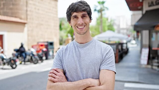 Young hispanic man smiling confident standing with arms crossed gesture at street