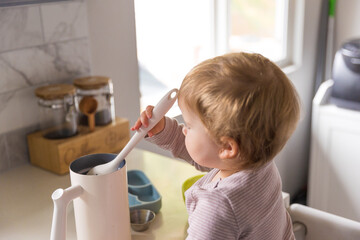 Toddler playing in the kitchen with household objects