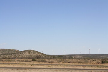 midwestern landscape with wind turbines creating renewable energy against a clear blue sky