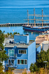 Fototapeta na wymiar Pirate ship in San Francisco Bay with blue house overlooking water