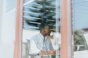 Businessman discussing with coworkers during meeting at the office. Shot through window.