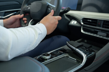 Naklejka premium Close-up of a man's hands on the steering wheel of a modern car. 