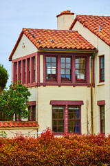 Fototapeta na wymiar Fort Mason white building with maroon windows and orangish red tile roof with reddening bush