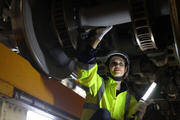 Female Rail engineer doing repair and maintenance of the power train of the electric trains in maintenance stations.