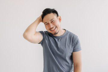 Shy and embarrassment funny asian man in blue t-shirt isolated on white wall. - obrazy, fototapety, plakaty