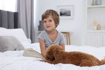 Little child and cute puppy on bed at home. Lovely pet