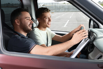 Driving school. Happy student passing driving test with examiner in car at parking lot