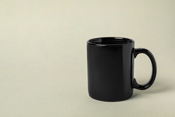 One black ceramic mug on light grey background, space for text