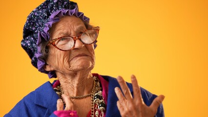 Closeup of angry, scared elderly senior old funny crazy woman with wrinkled skin and grey hair put hands out ask WHY ME, isolated on yellow background studio. People emotions - obrazy, fototapety, plakaty
