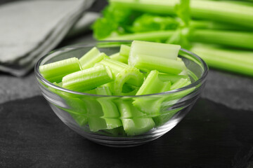Bowl with fresh green cut celery on grey table, closeup