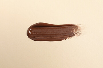 Fototapeta premium Smear of skin foundation on beige background, top view