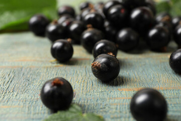 Ripe blackcurrants and leaves on wooden rustic table, closeup