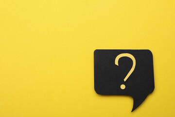 Paper speech bubble with question mark on yellow background, top view. Space for text