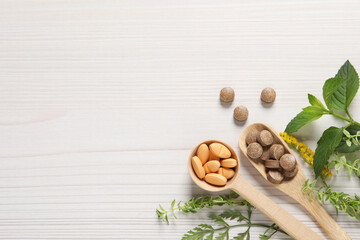 Different pills and herbs on white wooden table, flat lay with space for text. Dietary supplements
