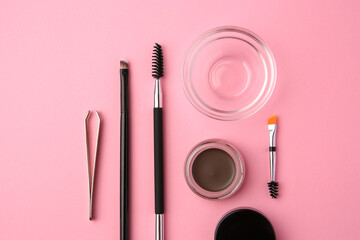 Eyebrow pomade with henna effect and professional tools on pink background, flat lay