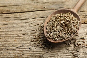 Spoon with caraway seeds on wooden table, closeup. Space for text