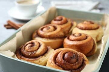 Baking dish with tasty cinnamon rolls on table, closeup
