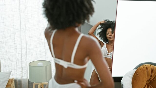 African american woman lingerie model looking on mirror posing at home