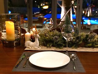 close up dining table setting for Christmas eve family party with deer decoration and wine glass