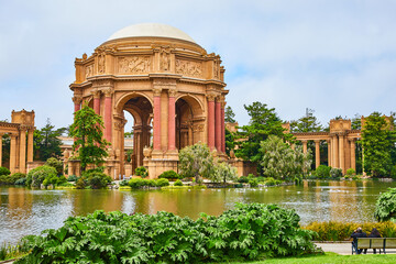 Couple sitting on bench looking across lagoon at Palace of Fine Arts admiring Roman architecture