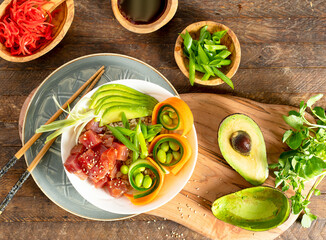 Poke on a wooden table, above view with ahi tuna, edamame, soy sauce and avocado