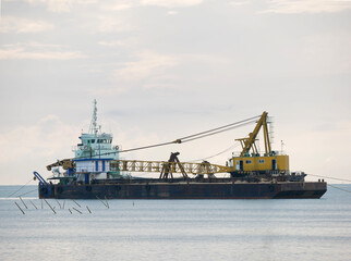 a large floating dredging excavator on sea coast