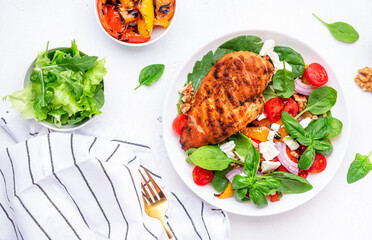 Healthy salad with grilled paprika and chicken, feta cheese, cherry tomatoes, walnut, red onion and lettuce, white table background, top view