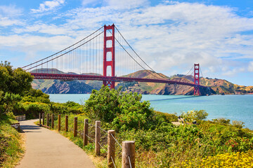 Trail leading to Golden Gate Bridge in San Francisco Bay on cloudy blue sky day