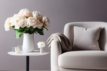 Vase of white peonies with coffee table and armchair near grey wall.