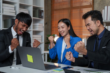 Group of Asian businessmen standing, smiling, raising their hands happily, sitting at a table in the office. A group of successful Asian business teams discuss collaboration and analyze company work.