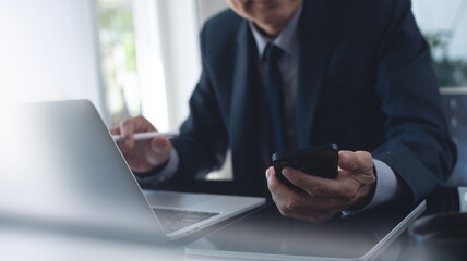 Businessman busy working at office, using mobile smart phone and working on laptop computer with digital tablet on office desk. 