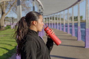 Portrait of a Latin girl drinking water from a bottle.