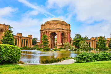 Palace of Fine Arts across lagoon water with cloudy blue sky overhead