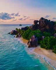 Wall murals Anse Source D'Agent, La Digue Island, Seychelles Anse Source d'Argent beach, La Digue Island, Seyshelles, Drone aerial view of La Digue Seychelles bird eye view, couple men and woman walking at the beach during sunset at a luxury vacation