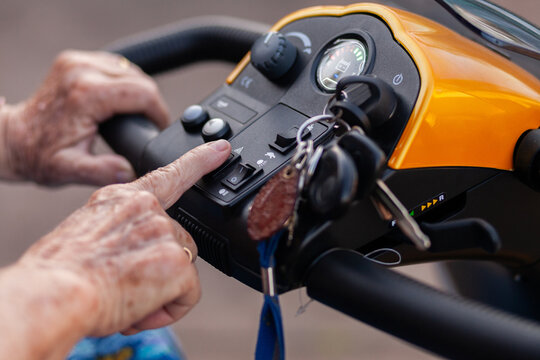 senior persons hands pushing buttons on electric mobility scooter vehicle