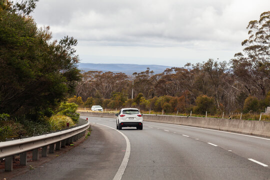 Single car driving around bend in highway road in western NSW