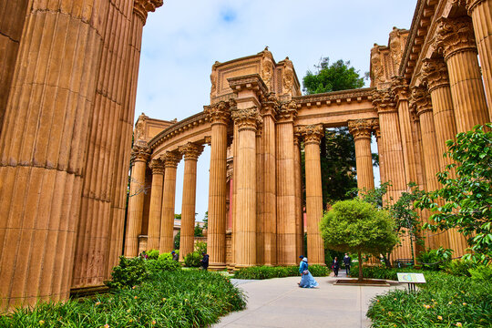 Roman colonnade pillars at Palace of Fine Arts with people walking on sidewalk