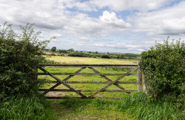 an old rotting wooden gate leading to a rolling meadow, Cumbria, UK