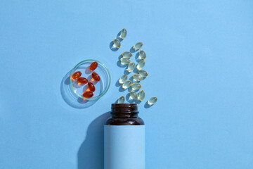 A white-labeled medicine bottle for text design, vitamin E pills scattered, fish oil capsules in a...