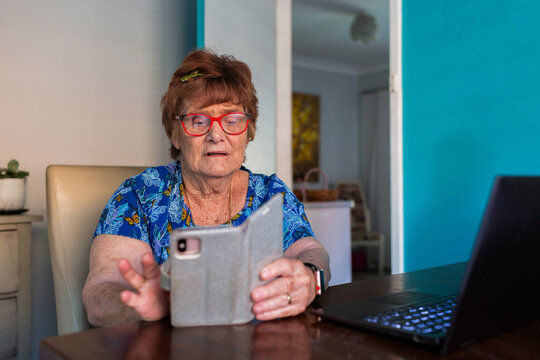 Senior lady using mobile phone inside at table looking worried