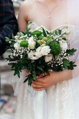 delicate wedding white-green bouquet in the hands of the bride in a rustic style