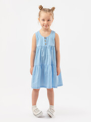 A guilty child. A 5-year-old girl stands on a white background with her hands down in a blue dress and sneakers. Copy Space
