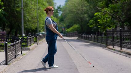 Blind pregnant woman crosses the street with the help of a tactile cane.